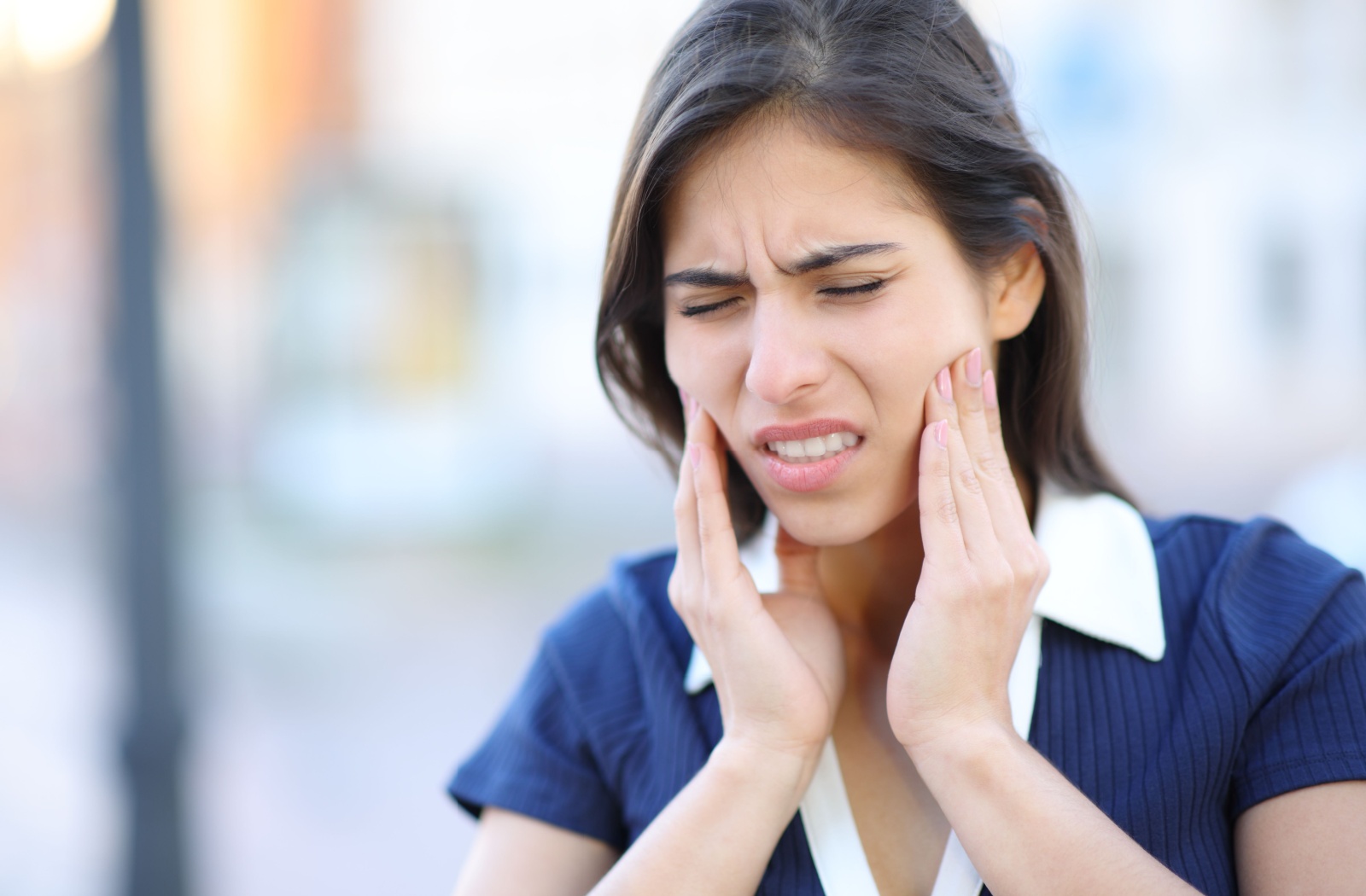 A woman suffers uncomfortable jaw pain due to TMJ Disorder