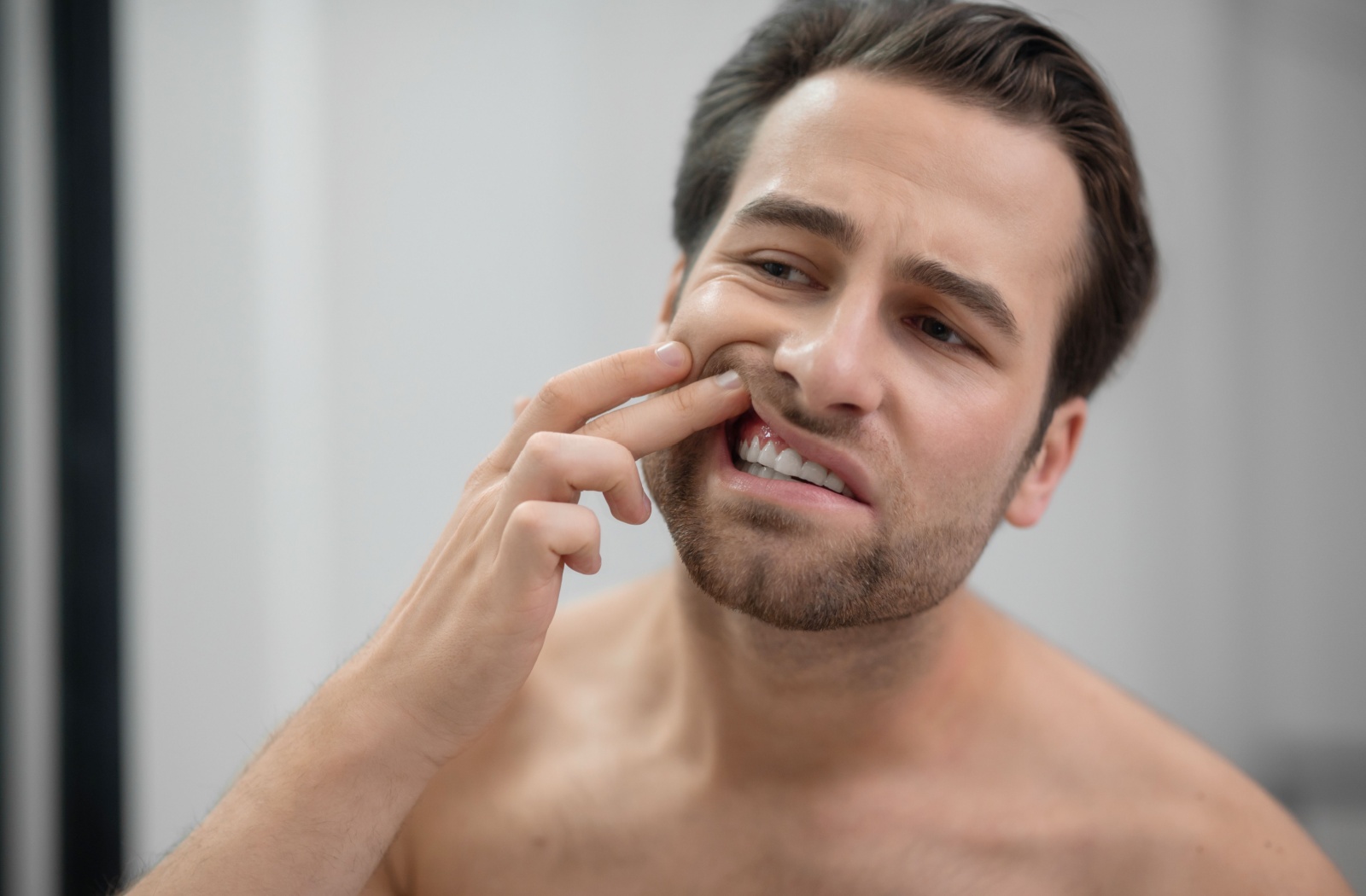 A person checks their gums in the mirror for bleeding after flossing.